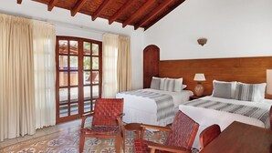 Habitación de hotel con dos camas, techo de madera, puerta que da al exterior y una silla.