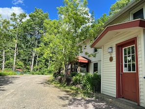 A house with a red door, a covered porch, and a gravel driveway.