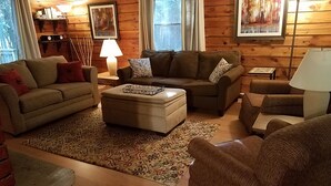 A cozy living room with a brown sofa set, a matching ottoman, and a patterned rug.