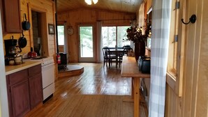 A wooden cabin interior with a kitchen, dining area, and a fireplace. - Cozy Lake Front Cabins For A Wonderful Summer, Fall and Winter fun Get Away!
 (Emily)
