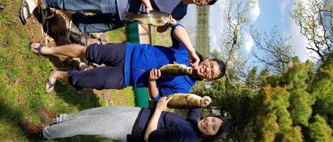 Trois personnes se trouvent à l’extérieur, près d’une étendue d’eau, et l’une d’entre elles tient un poisson.