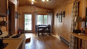 A wooden cabin interior with a kitchen, dining area, and a large window. - Cozy Lake Front Cabins For A Wonderful Summer, Fall and Winter fun Get Away!
 (Emily)