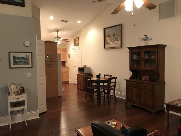 A spacious living room with hardwood floors, a dining area with a wooden table and chairs, a kitchen with wooden cabinets, and a ceiling fan. - Hobe Sound Natural Setting. New lightning fast internet. Great seclusion! (Hobe Sound)