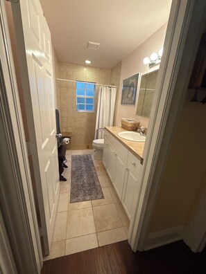 A narrow bathroom with a shower, toilet, and sink. - Hobe Sound Natural Setting. New lightning fast internet. Great seclusion! (Hobe Sound)