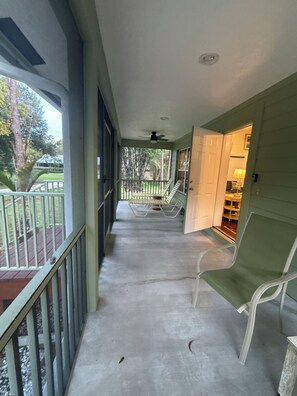 A covered porch with a concrete floor, a ceiling fan, and a view of a backyard with a lawn and trees. - Hobe Sound Natural Setting. New lightning fast internet. Great seclusion! (Hobe Sound)