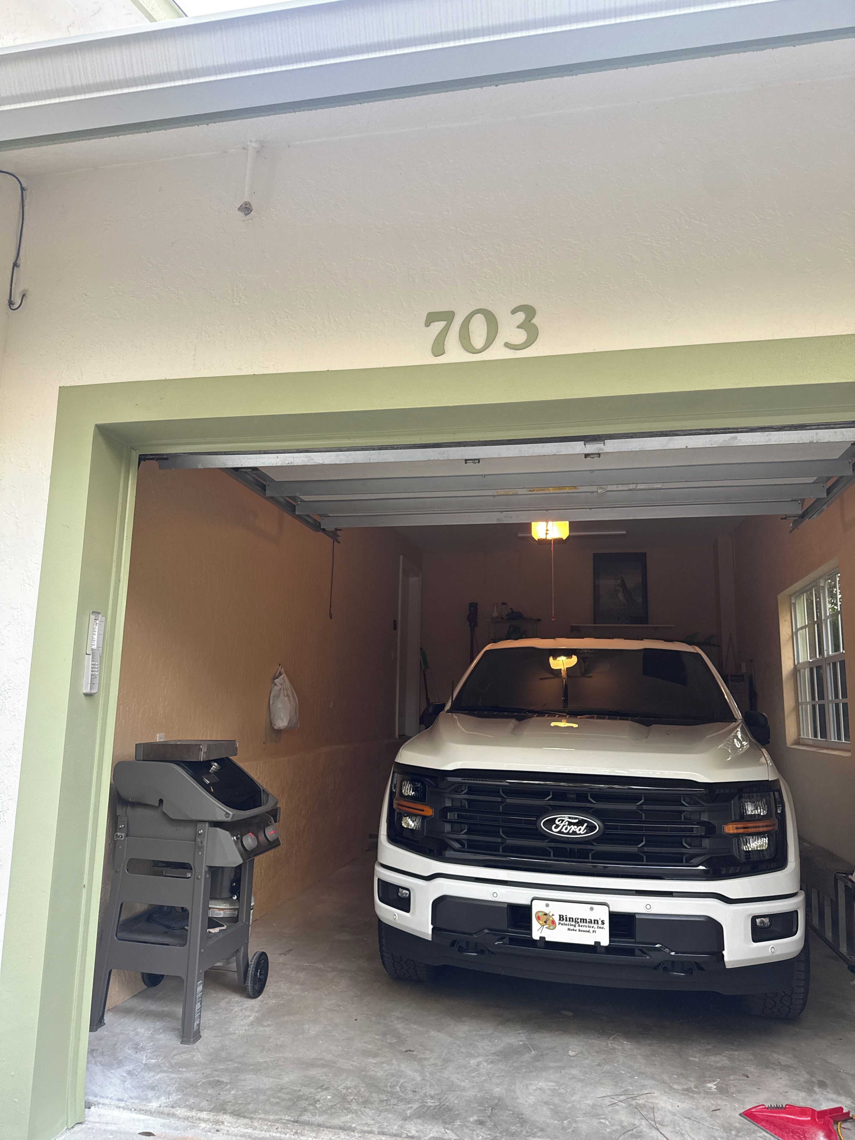 Una camioneta Ford blanca estacionada dentro de un garaje con el número 703 en la pared.