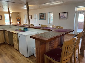 Una cucina con mobili in legno, un frigorifero bianco e un'area pranzo con sedie e tavolo in legno.