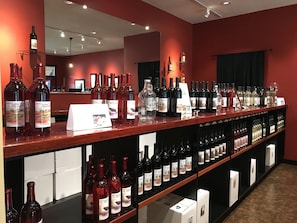 Una sala dedicata alla degustazione di vini, con scaffali pieni di bottiglie e un bancone con un cartello.