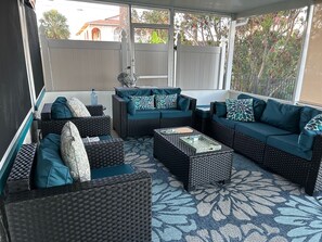 A covered outdoor seating area with wicker furniture and patterned cushions.