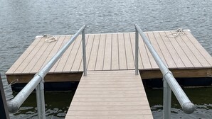 Eine hölzerne Anlegestelle mit Metallgeländern, die sich über ruhiges Wasser erstreckt.