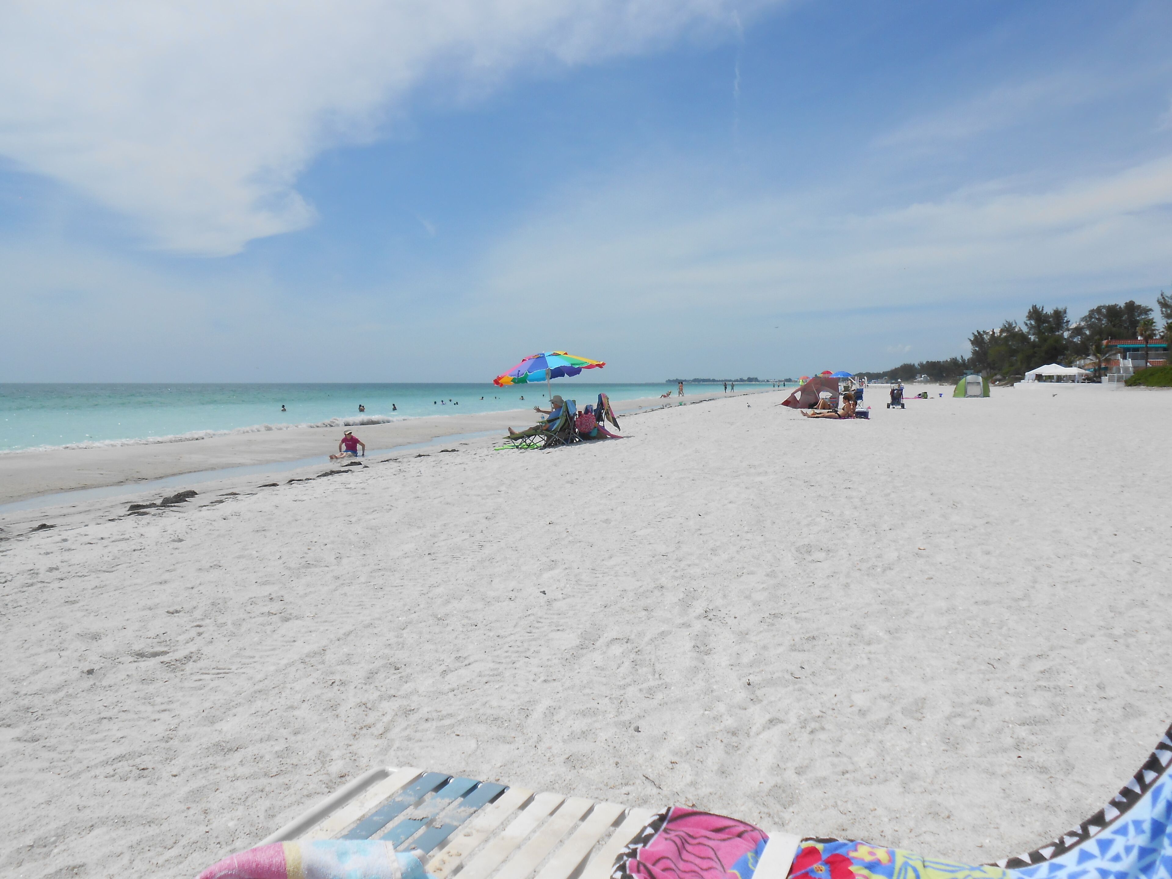 Una playa con arena, algunas sombrillas y algunas personas.