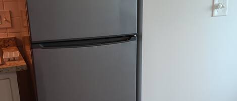 Una cocina moderna con un refrigerador gris, una pequeña encimera e interruptor de luz en la pared.