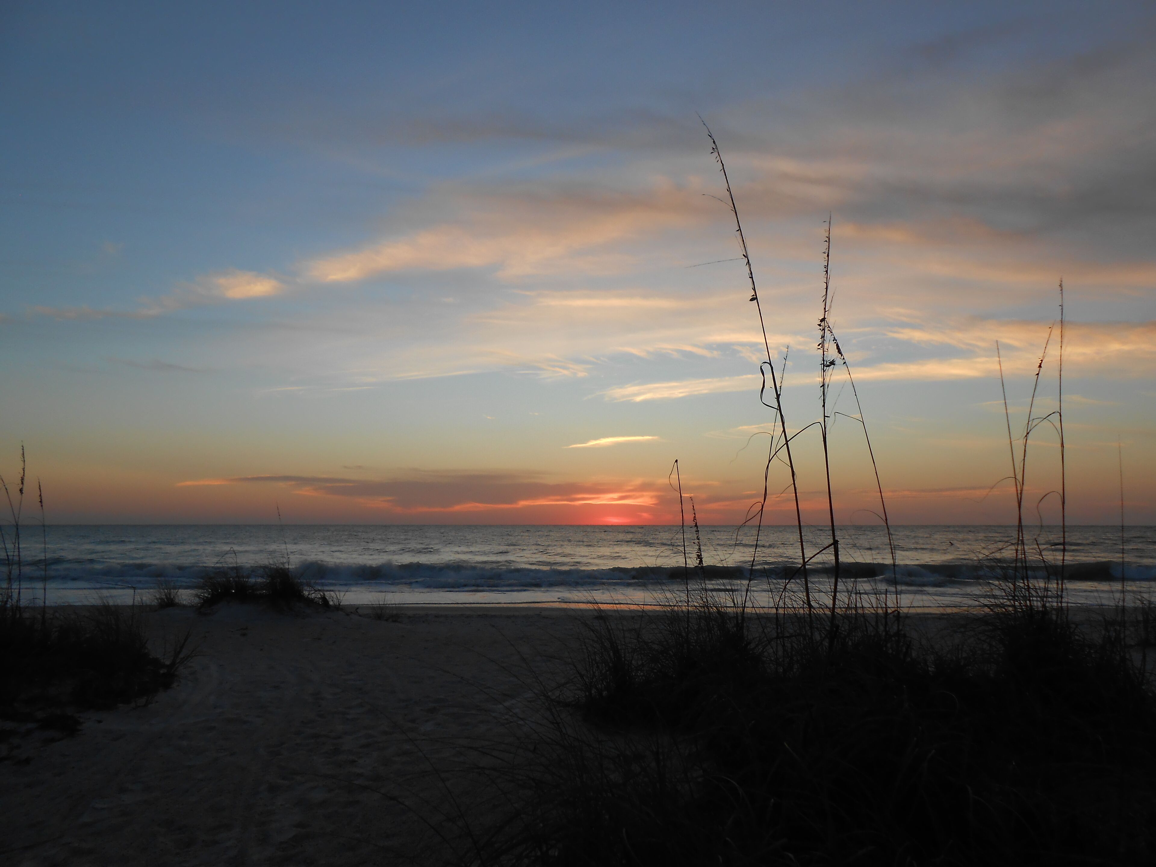 Ein Strand mit Sonnenuntergang im Hintergrund.