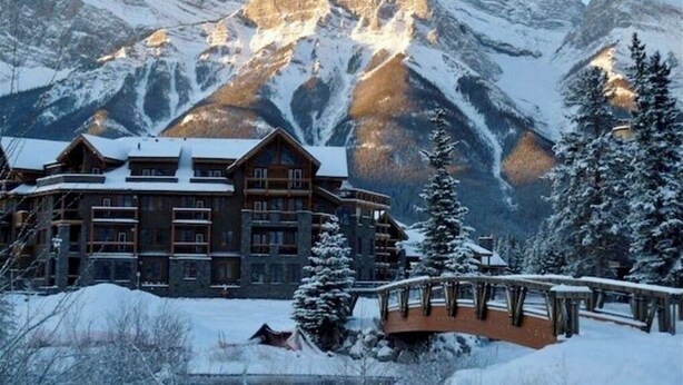 A lodge with multiple floors, a wooden exterior, and a view of snow-covered mountains. - Premium penthouse in the heart of the Canadian Rockies! Walk to busy downtown. (Canmore)