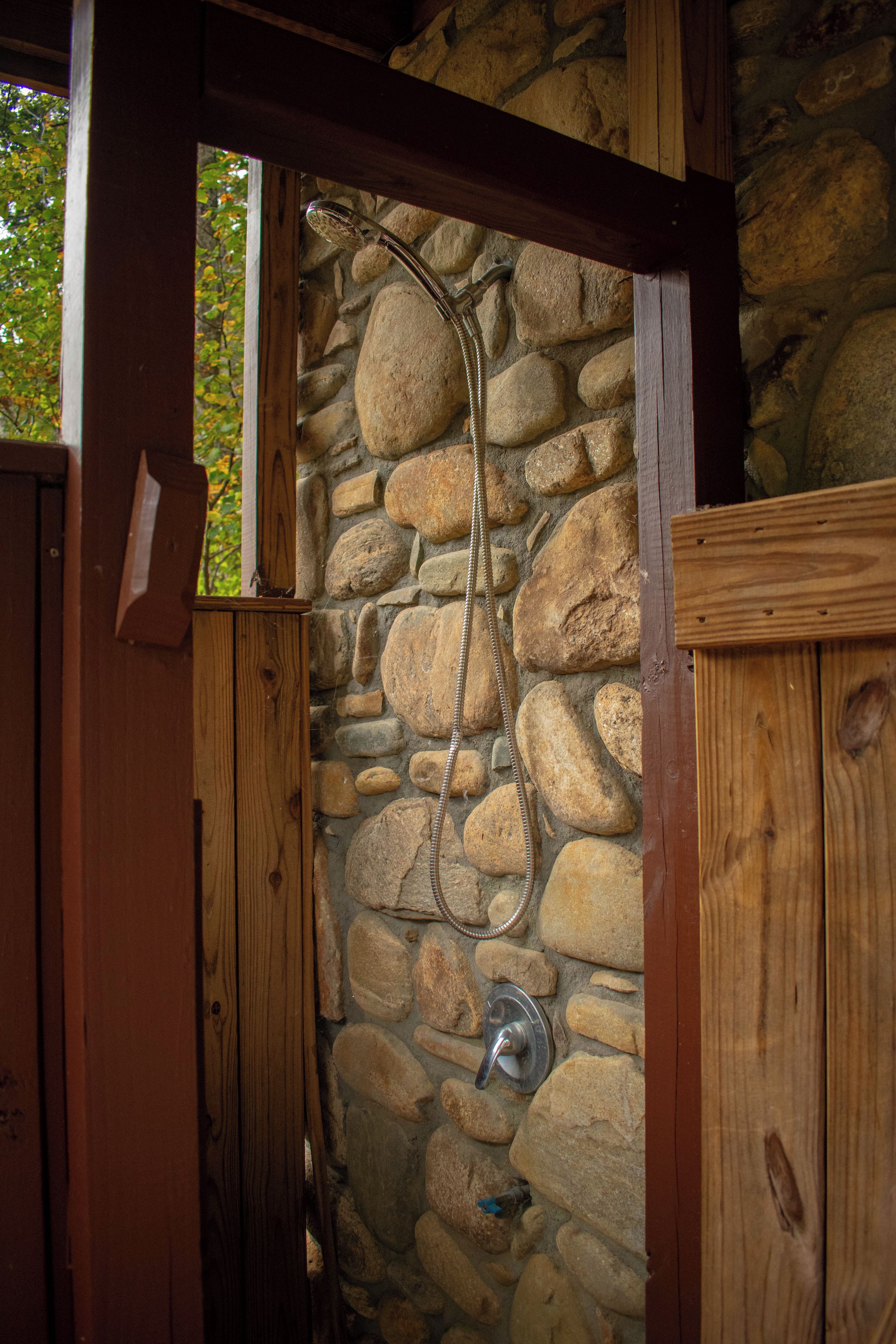 A stone wall with a metal shower fixture.