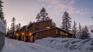 A wooden lodge with multiple rooms, a snow-covered driveway, and tall pine trees in the background. - LUXURY VIEW CONDO/SKI-IN/SKI-OUT/TO CANYON/EAGLE EXPRESS (Mammoth Lakes)