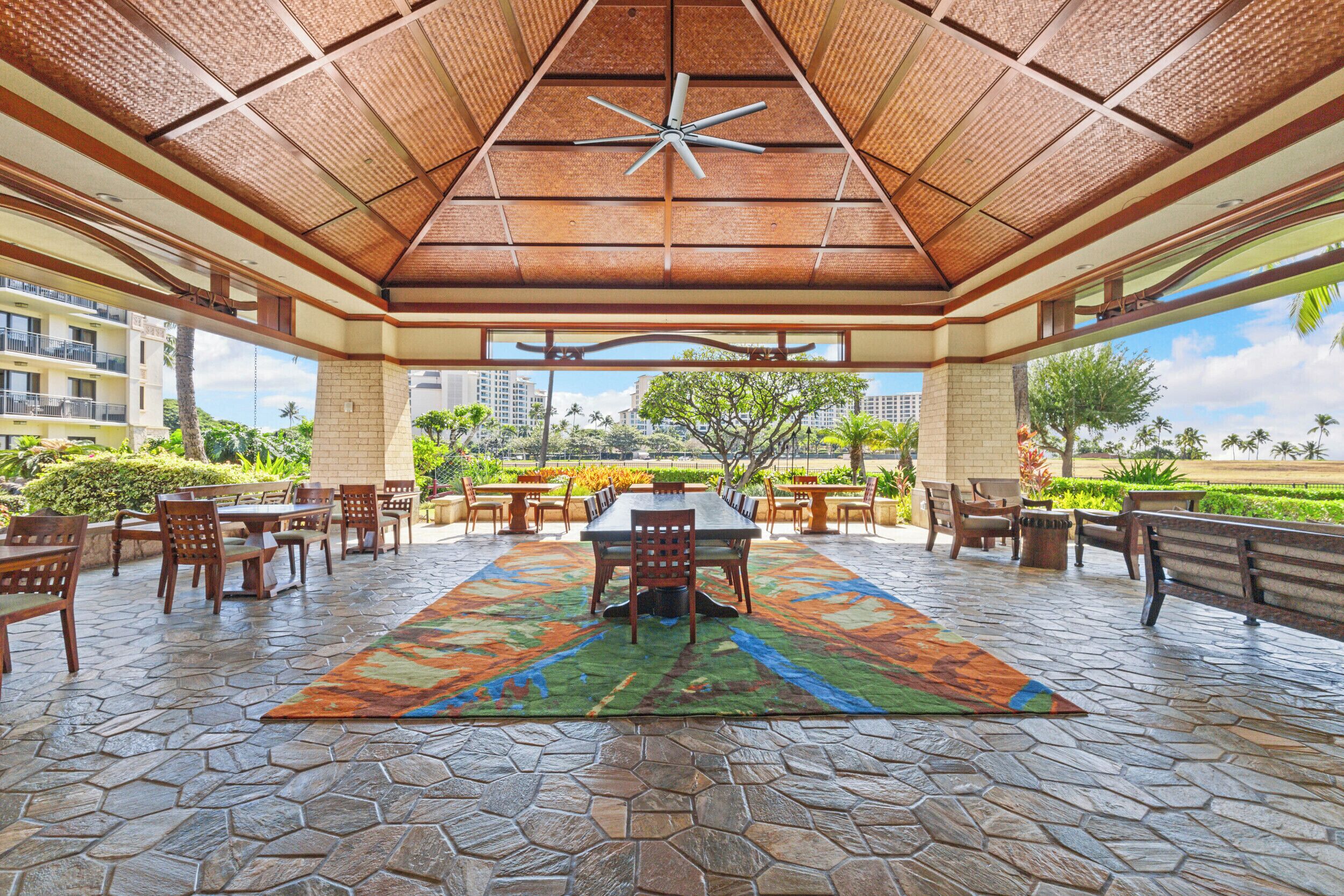 An outdoor patio with a central table, chairs, and a ceiling fan.
