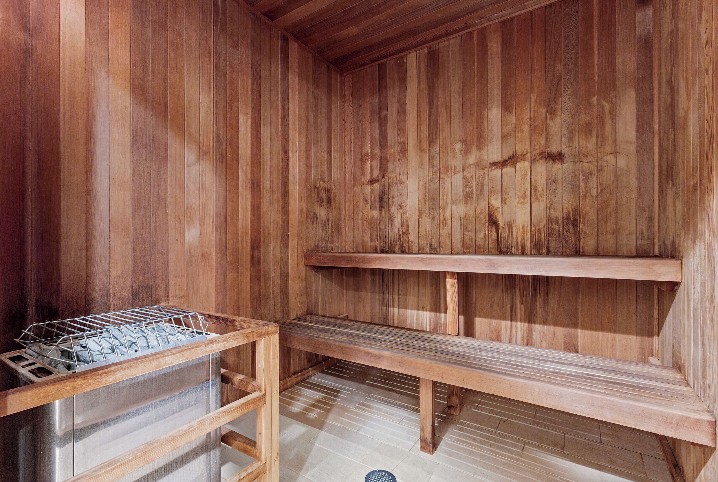 A wooden sauna with benches and a metal rack.