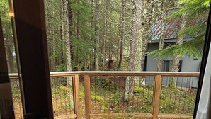 Eine Holzterrasse mit Metallgeländer, umgeben von Bäumen und einem Gebäude im Hintergrund.