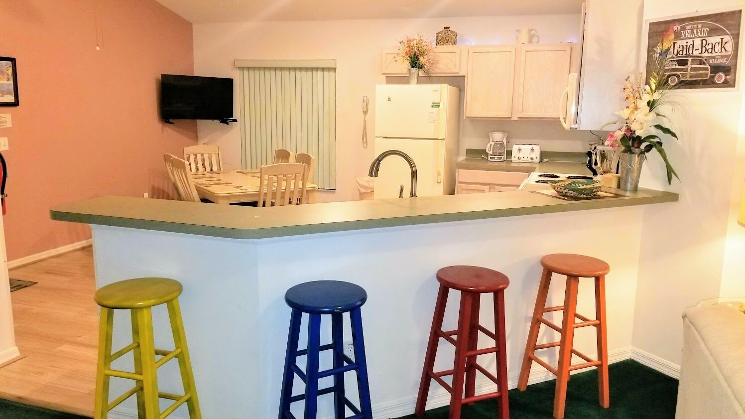 A compact kitchen with a central island, a dining area, and a bar stool arrangement.