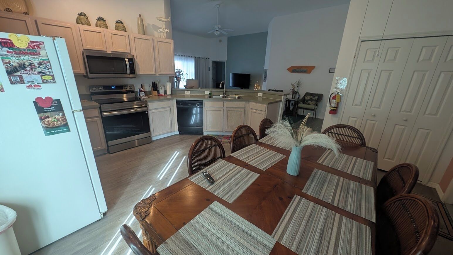 A modern kitchen with white cabinets, stainless steel appliances, and a dining area with a wooden table and chairs.