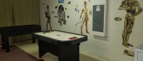 A room with a foosball table, Star Wars decorations, and a Star Wars-themed poster.