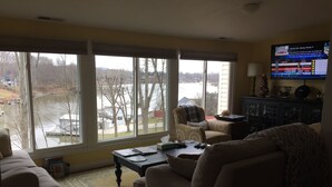 A living room with a large window, a television, a sofa, a coffee table, and a cabinet.