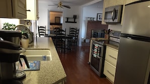 A kitchen with a refrigerator, microwave, oven, and a dining area with chairs and a table.
