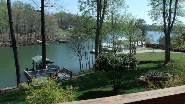 A lakeside property with a dock, a small pavilion, and a grassy area with trees.