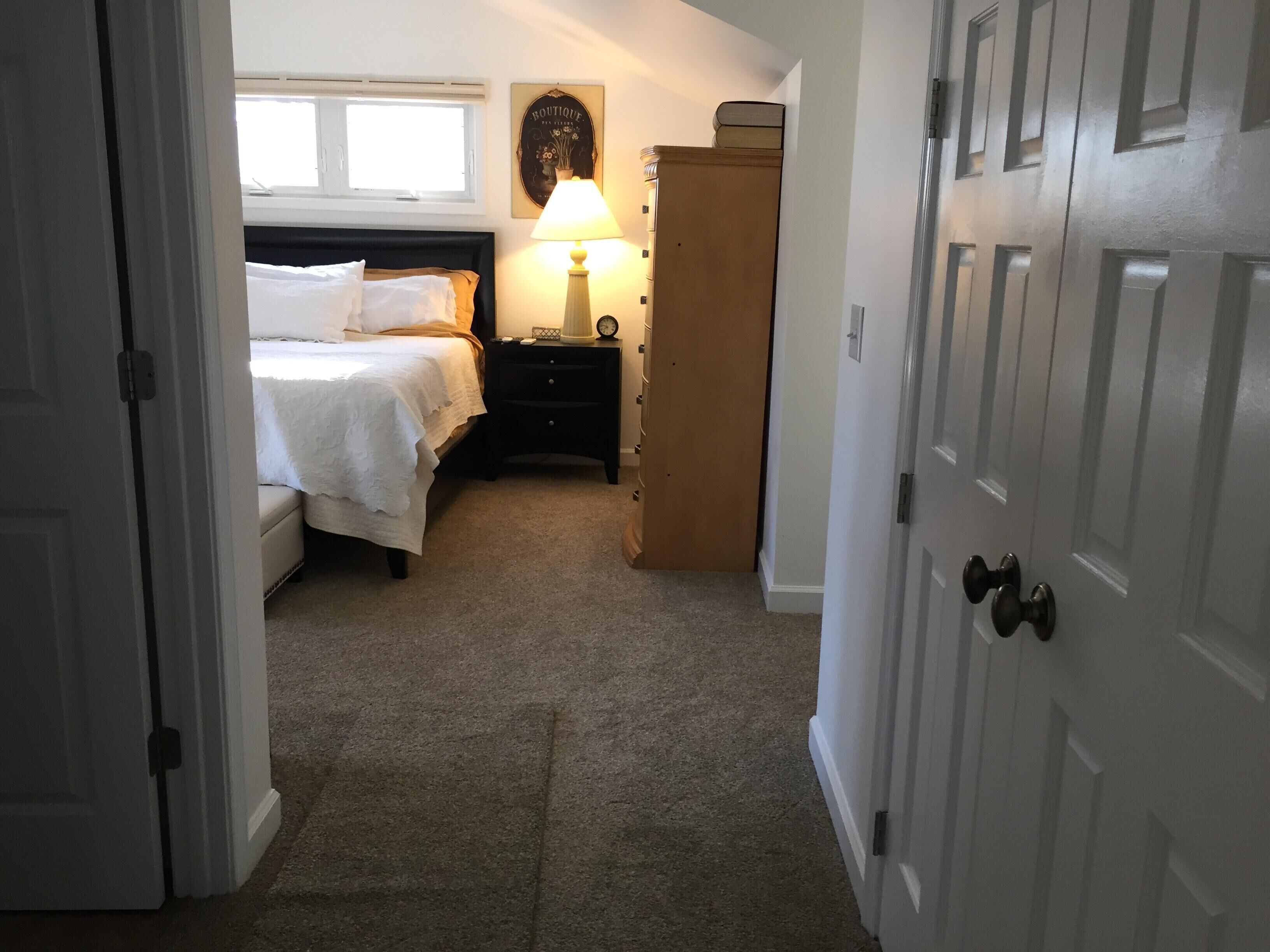 Quarto com cama, mesa de cabeceira, abajur e guarda-roupa.