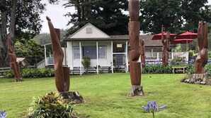 A garden with sculptures, a white building, and a red umbrella. - On the beach, Beautiful ocean views. (Kihei)