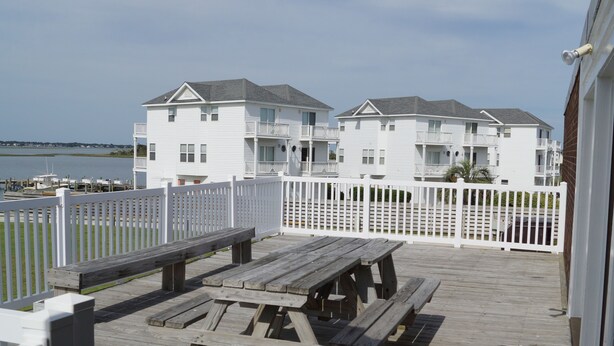 A wooden deck with picnic tables and a white fence. - Come for the beach, stay for the memories. Enjoy free beach access & huge pool! (Atlantic Beach)
