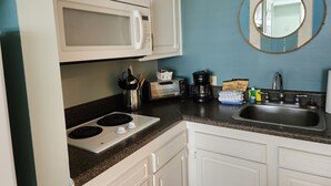 A kitchen with white cabinets, a microwave, a stove, a coffee maker, and a sink. - Come for the beach, stay for the memories. Enjoy free beach access & huge pool! (Atlantic Beach)
