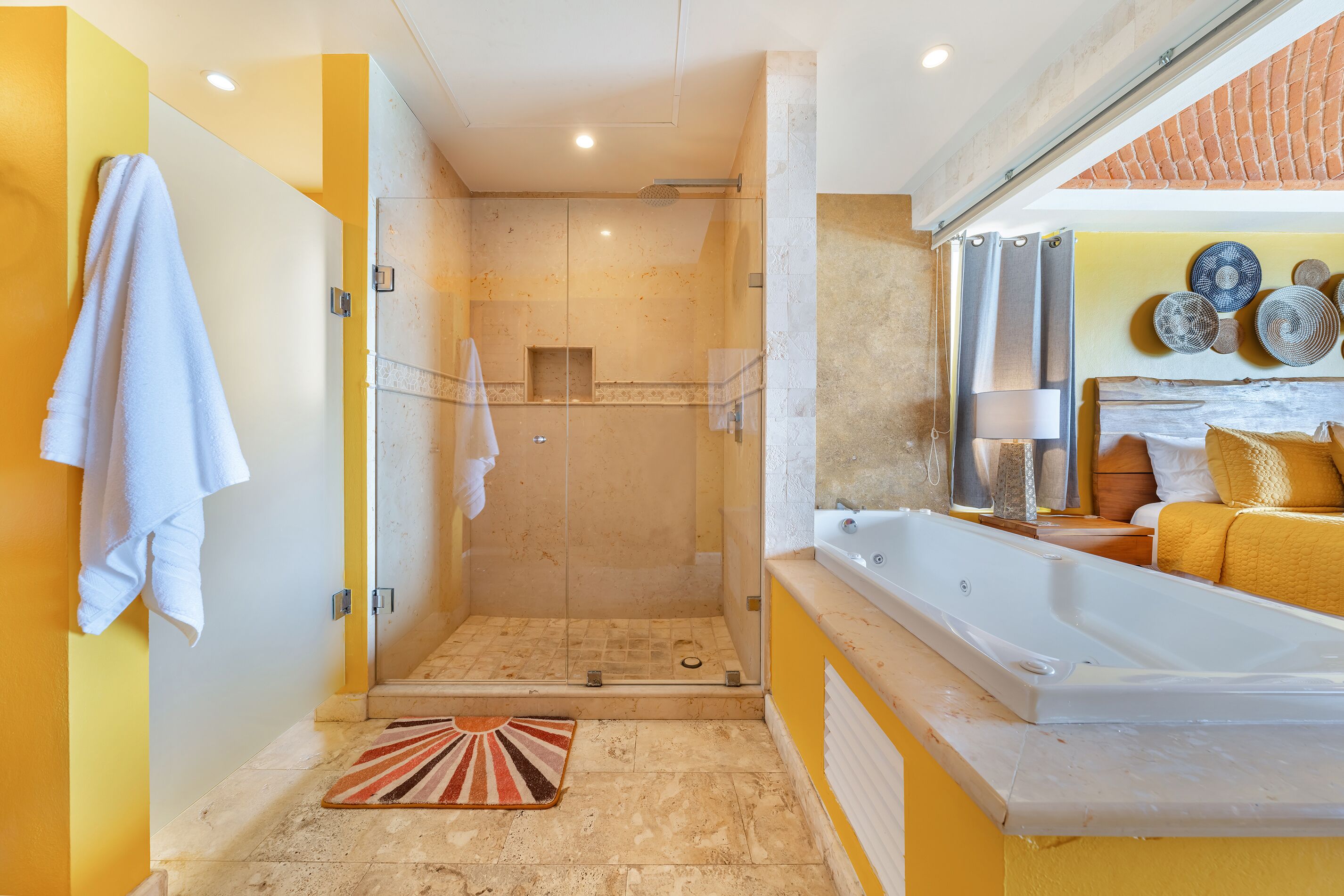 A modern bathroom with a glass-enclosed shower, a large bathtub, and a yellow accent wall.