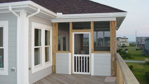 Ein Haus mit überdachter Veranda, weißem Klinker und dunklem Dach.
