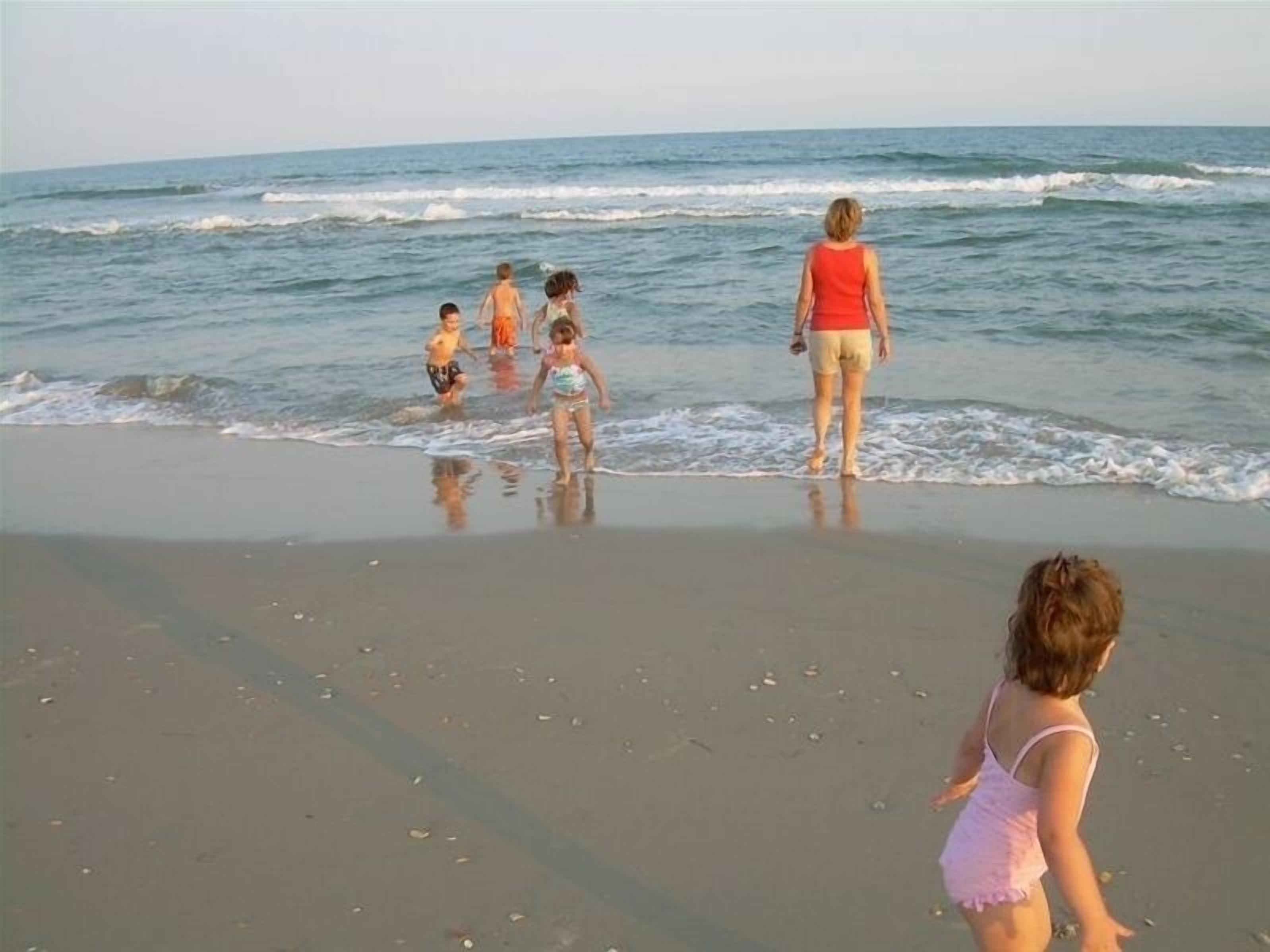 Escena de playa con gente caminando por la orilla.