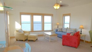 Ein Wohnzimmer mit Meerblick, einer Essecke und einem roten Sofa.