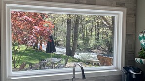Une cuisine dotée d’une grande fenêtre donnant sur un jardin aux couleurs automnales.