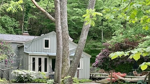 Une maison avec un porche et un ruisseau qui la borde.