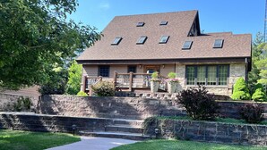 A two-story house with a stone facade, a sloped roof, and multiple windows. - Perfect For Family Reunions/Weekend Getaways/Large Groups. A hidden oasis! (Fish Creek)