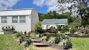 A white building with a green roof, surrounded by a landscaped garden with various plants and a wooden staircase. - River View Place / beautiful view (Fries)