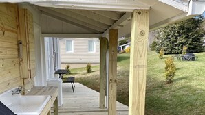 A covered outdoor deck with a sink and bench, supported by wooden posts. - River View Place / beautiful view (Fries)