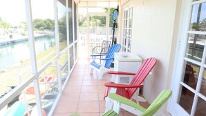 Un patio techado con vista a una piscina, con varias sillas coloridas y una mesa.