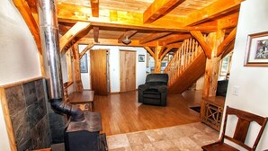 Un intérieur en bois avec une cheminée, un escalier et une chaise.