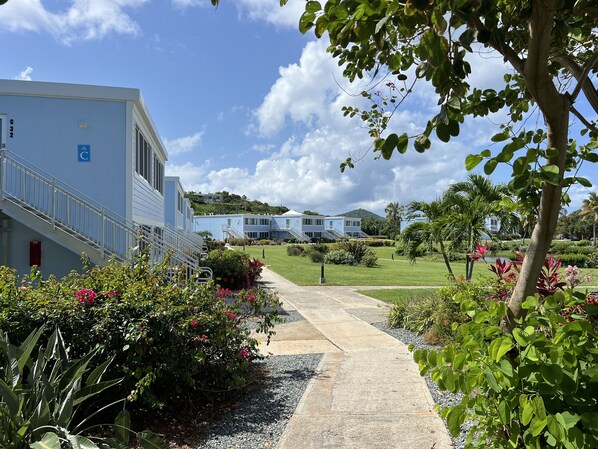 A pathway leading to a building with a blue exterior and a wheelchair-accessible ramp.
