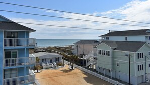 A beachfront property with multiple-story buildings, a sandy beach, and a pier extending into the ocean. - Carolina Beach Spectacular Views from Front & Back,  Pool & Wifi - Renovated (Carolina Beach)