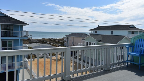 A beachfront property with a balcony overlooking the ocean, featuring a sandy beach and a pier. - Carolina Beach Spectacular Views from Front & Back,  Pool & Wifi - Renovated (Carolina Beach)