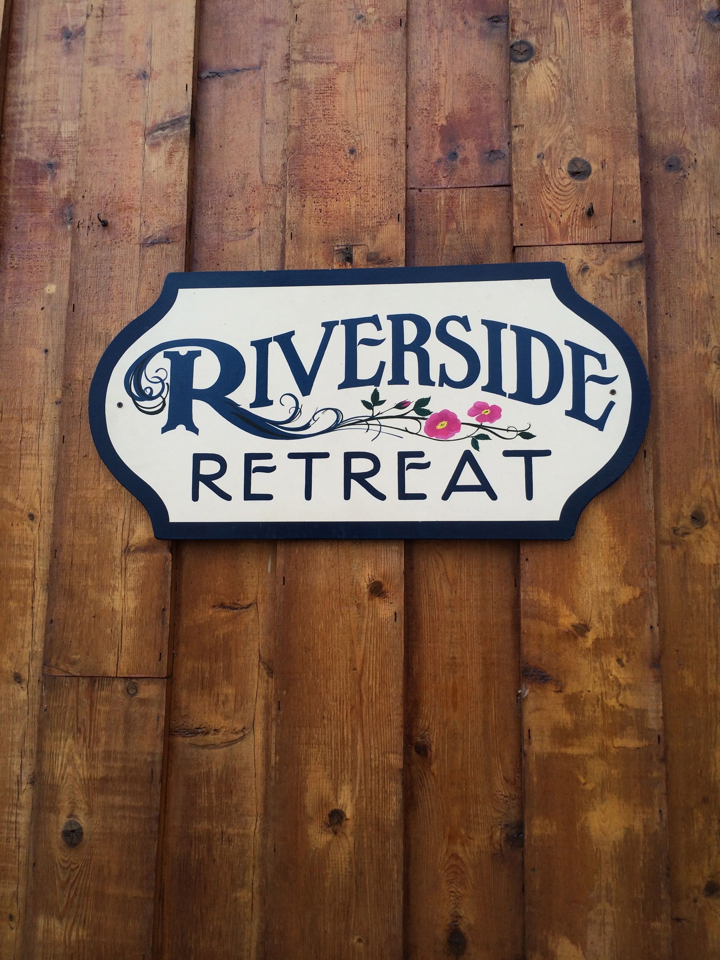 A sign for Riverside Retreat on a wooden background.