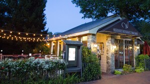 A restaurant with outdoor seating, string lights, and a stone facade.