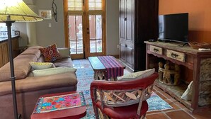 A living room with a sofa, a red chair, a wooden cabinet, and a television.